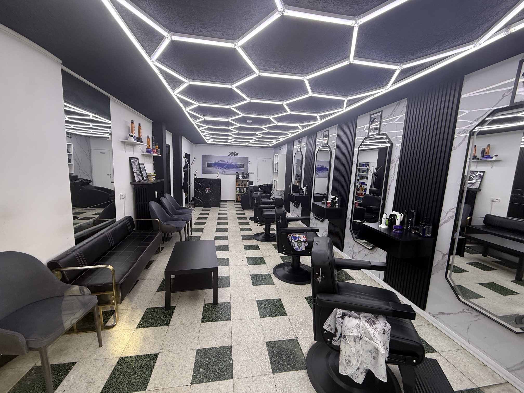Intérieur du salon ADN Hair : fauteuils de barbier, miroirs et plafond lumineux.